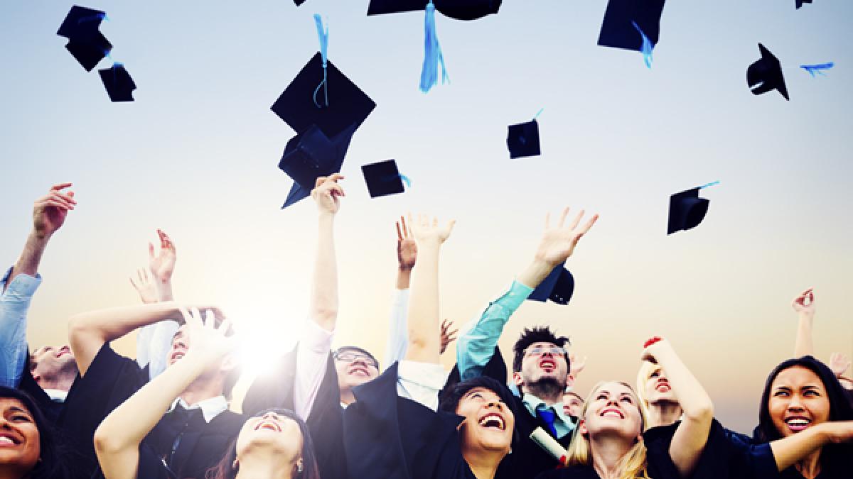 Graduates throwing mortar boards in the air